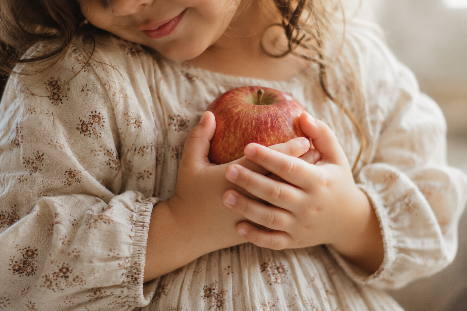 A child holding an apple close to their chest